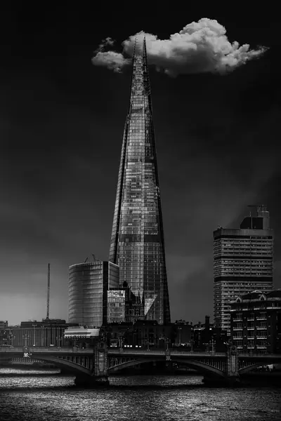 O edifício The Shard, em Londres, sob uma nuvem isolada, com uma ponte sobre o Tâmisa em primeiro plano